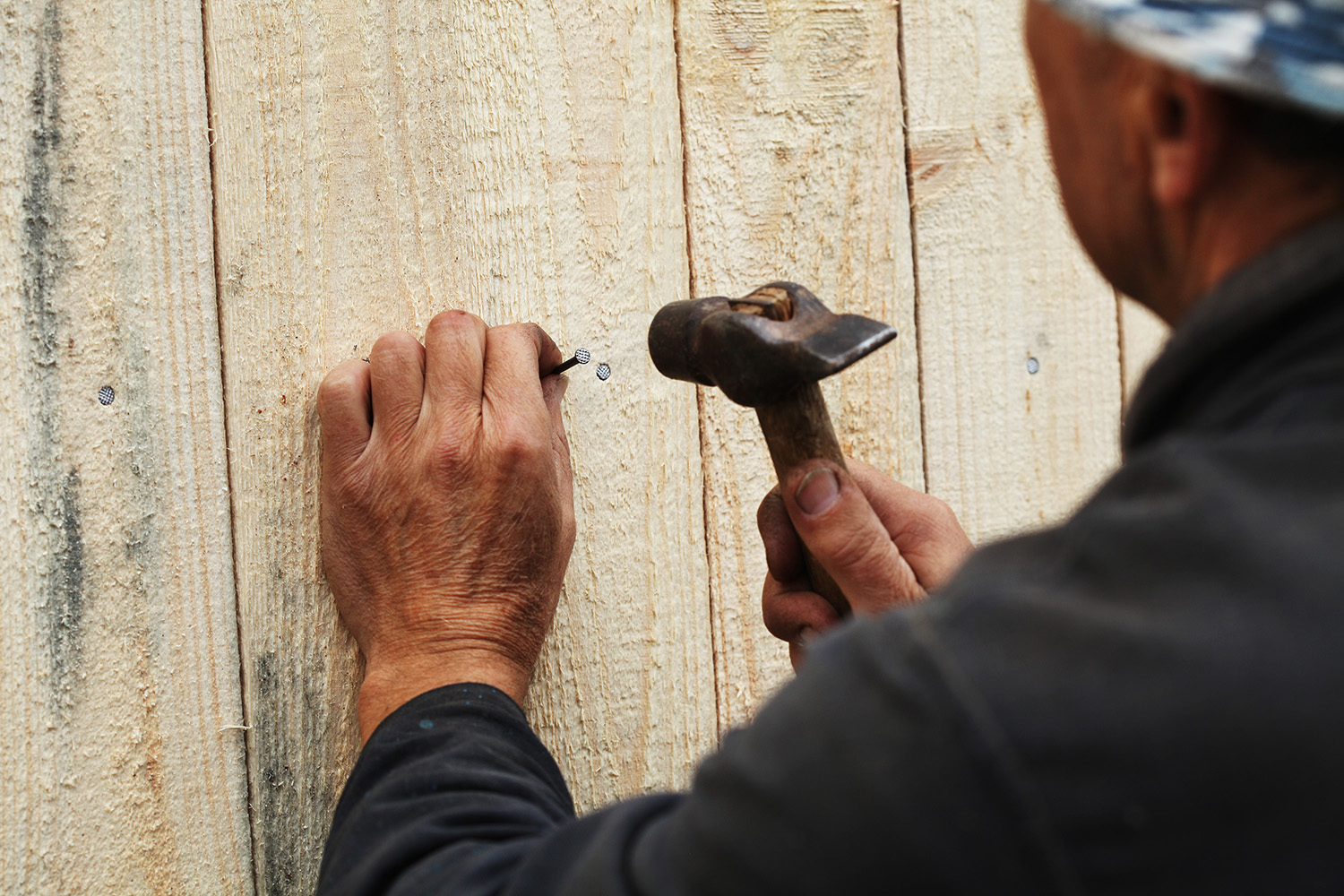 Handyman fixing wooden plank with a nail