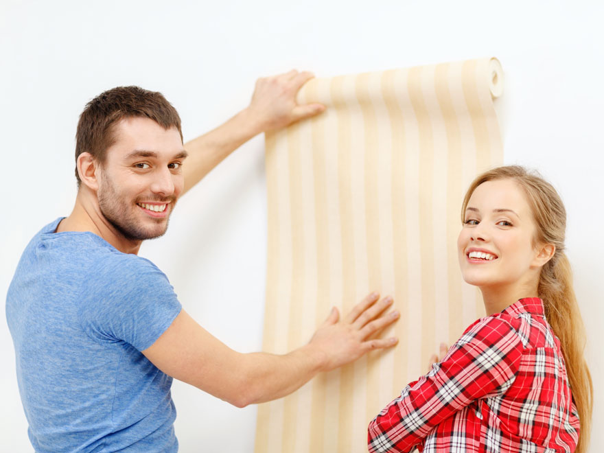 young couple hanging wall paper